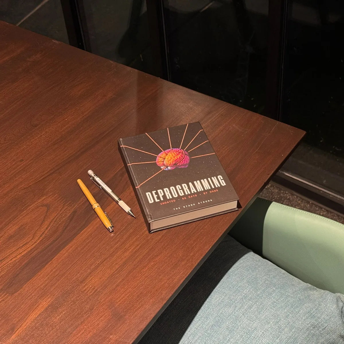The closed journal on a table, two pens beside it.